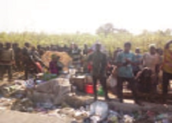 The scavengers in the middle of the refuse while people sell drinks.